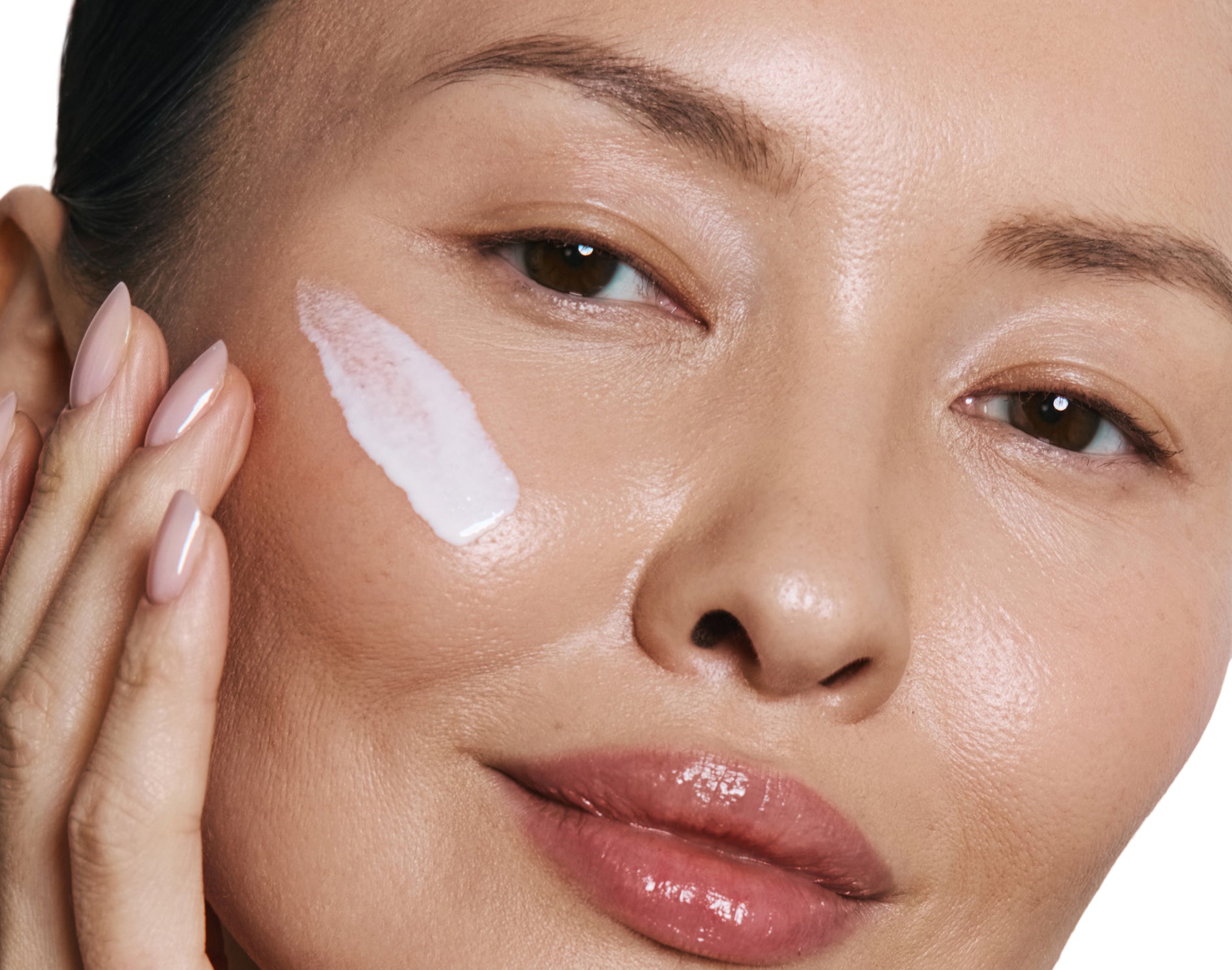Close-up of a woman's face with a white cream applied to her cheek.