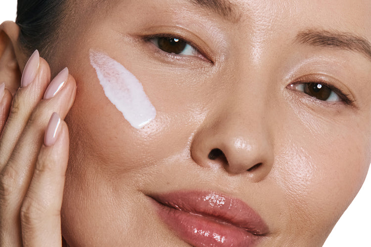 Close-up of a woman's face with a white cream applied to her cheek.