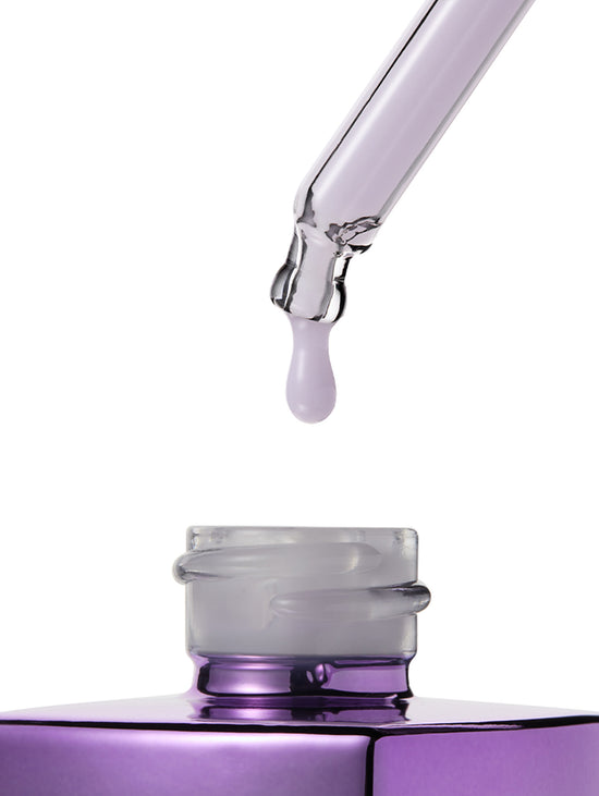 A close-up studio shot of a purple cosmetic dropper above an open purple bottle, with a single clear droplet hanging in the center against a white background.