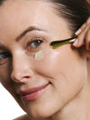 Woman applying an eye product to her face with a applicator.
