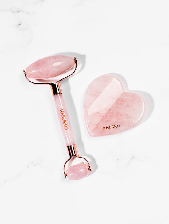 Knesko skincare tool set with pink heart-shaped roller and gua sha tool on a white background