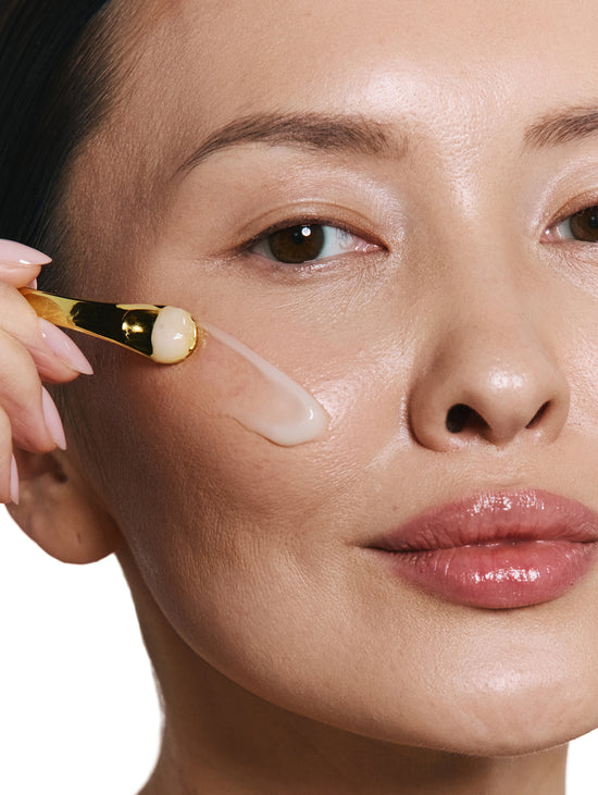 Woman applying a skincare product to her cheek with a applicator