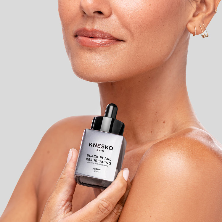 woman holding black pearl serum bottle 