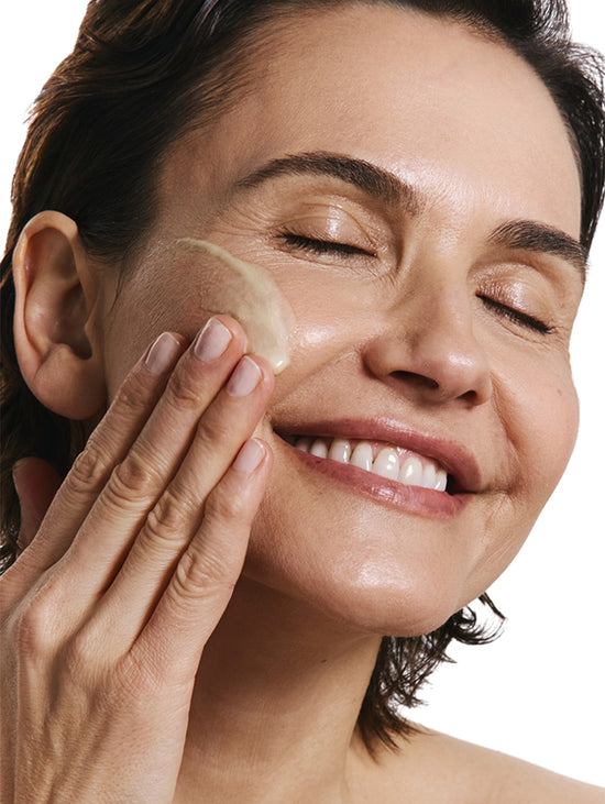 Woman applying a product to her face.