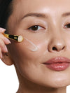 Woman applying a skincare product with a applicator to her face.