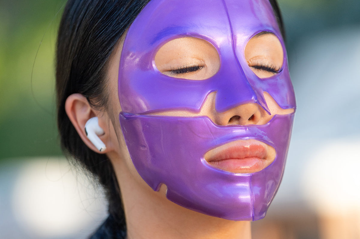 Woman wearing a purple face mask and headphones meditating outdoors