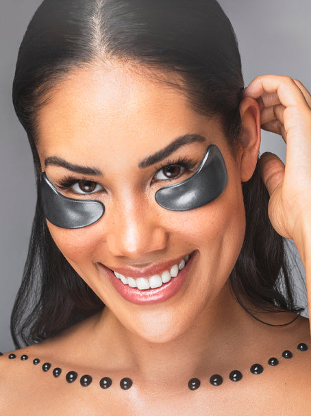 A woman using eye masks from the Black Pearl Detox collection.
