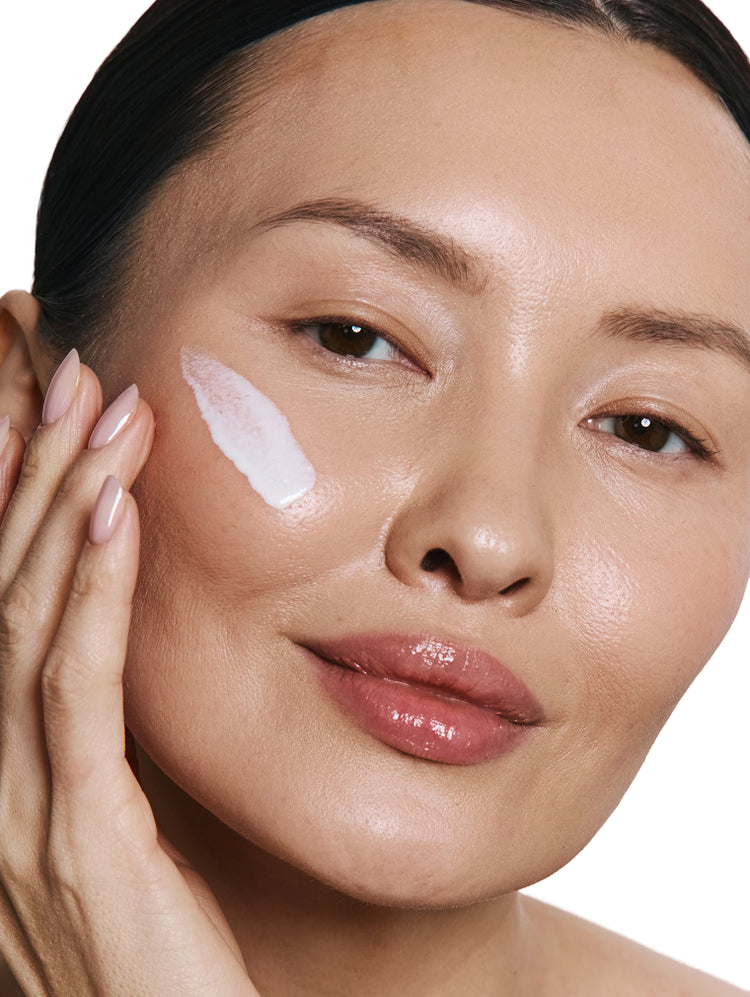 Close up of a woman applying cream to her face