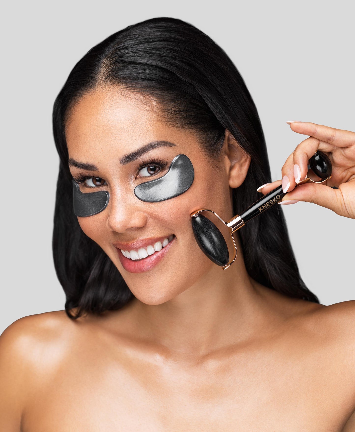 A woman using the Black Pearl Detox Collagen Mask & Obsidian Gemstone Roller Set.