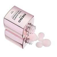 pink serum bottle that says knesko skin rose quartz antioxidant serum dripping onto the table.