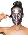 A woman using the Black Pearl Detox Collagen Mask & Obsidian Gemstone Roller Set.
